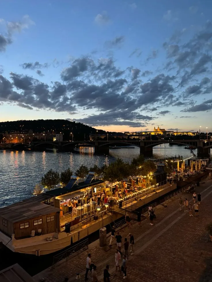 People at the Náplavka riverbank bars on the Vltava at dusk